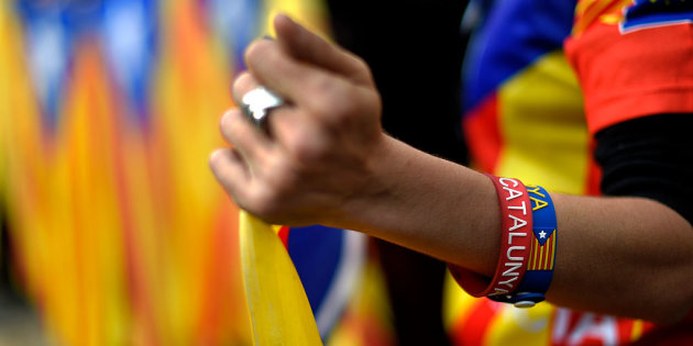 A demonstrator sporting wristbands with the word "Catalunya" on them hold pro-independence Catalan flags during a demonstration in front of the headquarters of the Catalan Government to demanding an agreement between secessionist parties in Barcelona on January 9, 2016. AFP PHOTO / LLUIS GENE / AFP / LLUIS GENE (Photo credit should read LLUIS GENE/AFP/Getty Images)